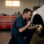 Mechanic inspecting car brakes in garage