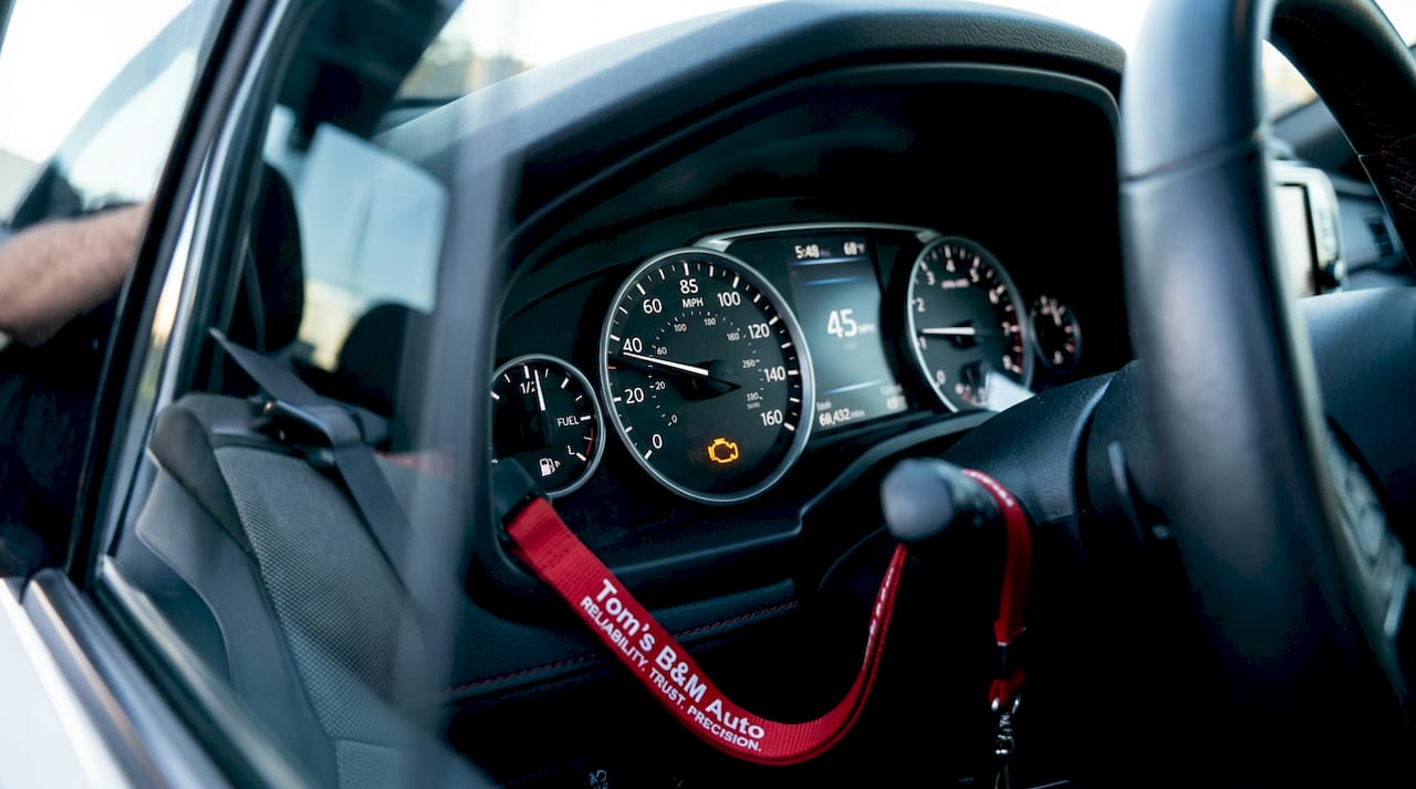 Car dashboard with illuminated check engine light