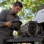 Technician inspecting vehicle transmission parts