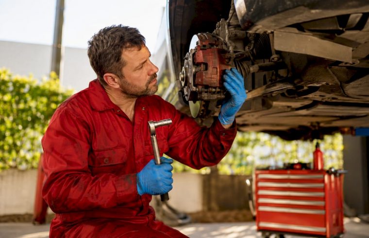 Technician inspecting brake caliper on vehicle wheel