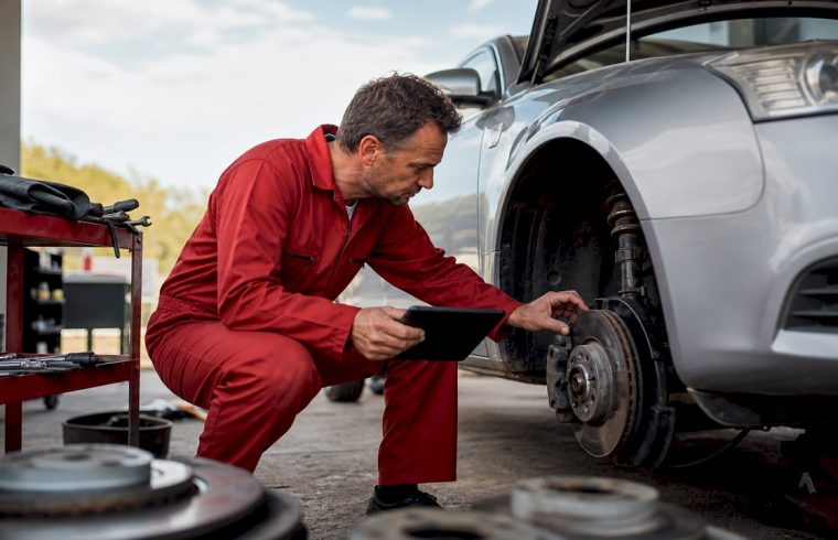 Mechanic inspecting car brake system in garage