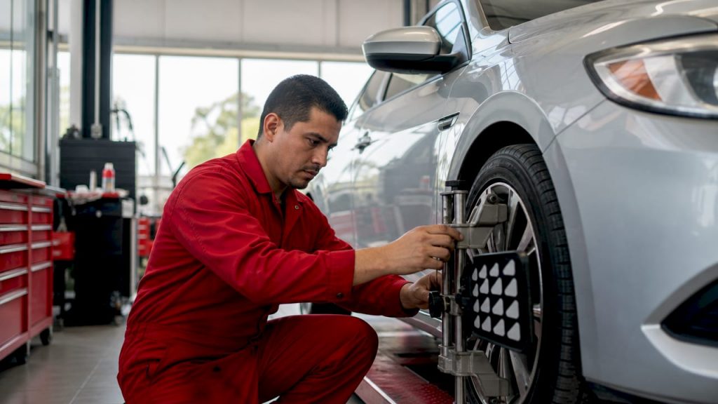 Mechanic checking tire pressure on car's front wheel