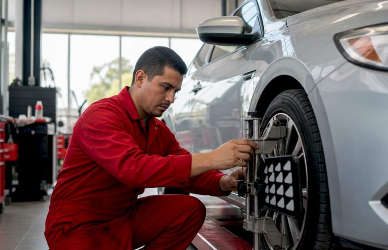 Mechanic checking tire pressure on car's front wheel