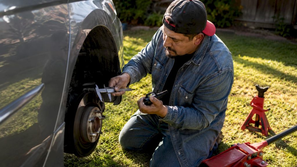 Man inspecting brake pads on car outdoors
