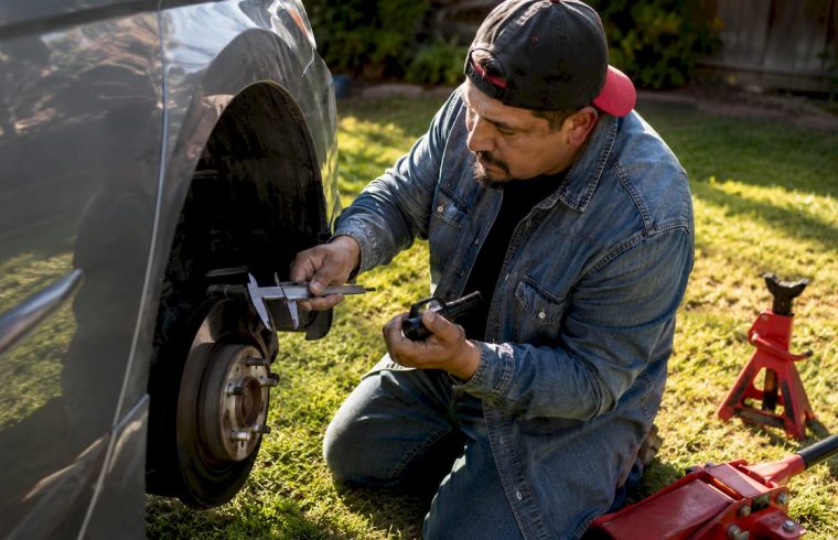 Man inspecting brake pads on car outdoors