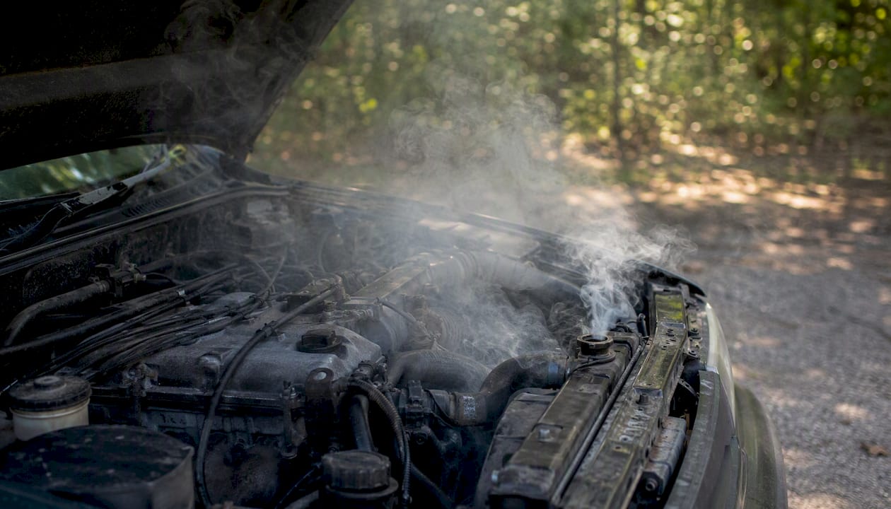 Overheated car engine with smoke under open hood