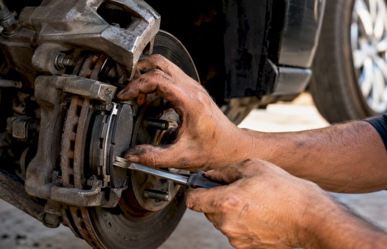 Technician replacing brake pads on vehicle wheel