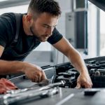 Technician inspecting car engine under hood