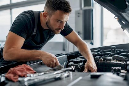 Technician inspecting car engine under hood