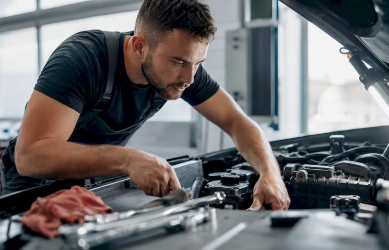 Technician inspecting car engine under hood