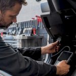 Technician connecting diagnostic scan tool in auto bay