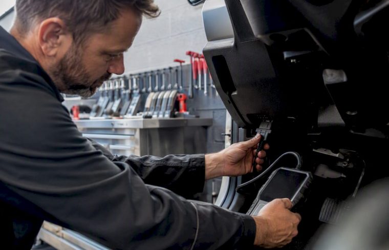 Technician connecting diagnostic scan tool in auto bay