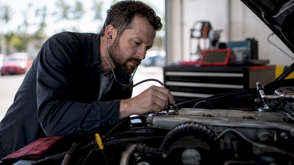 Technician checking engine timing chain noise