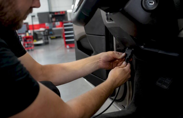 Technician plugging diagnostic tool into car dashboard