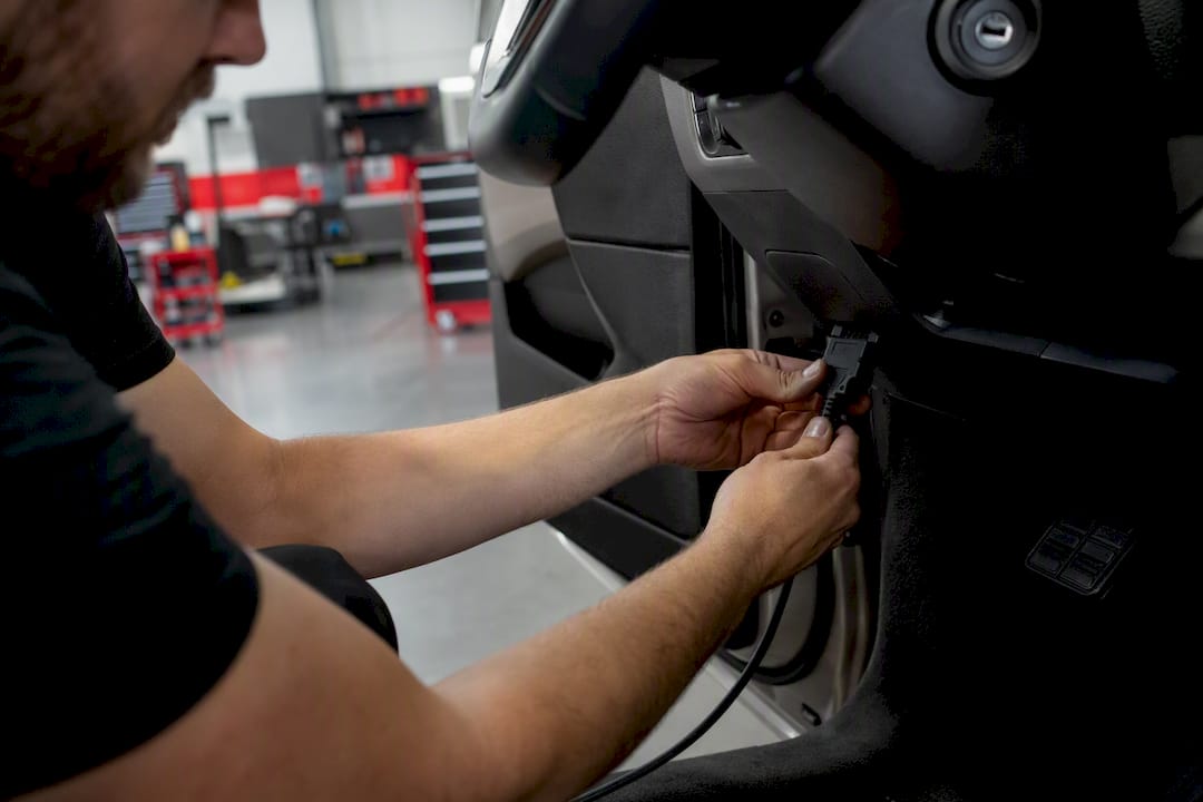 Technician plugging diagnostic tool into car dashboard