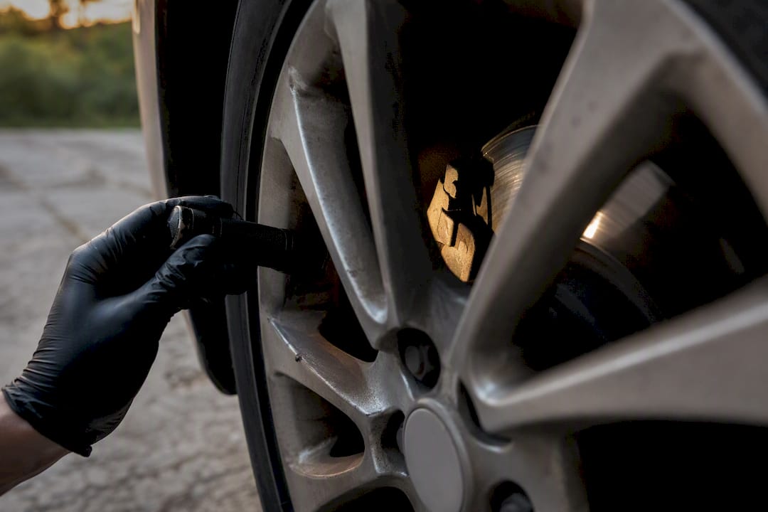 Gloved hand inspecting brake pads with flashlight