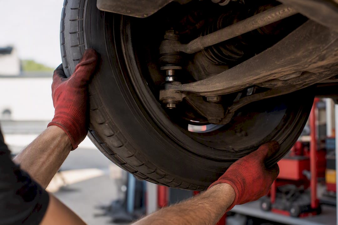 Hands checking ball joint wear on suspension