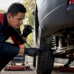 Mechanic listening to car suspension with stethoscope