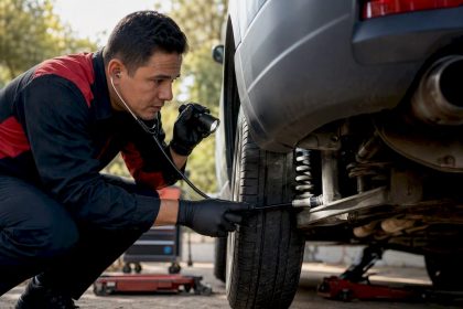 Mechanic listening to car suspension with stethoscope