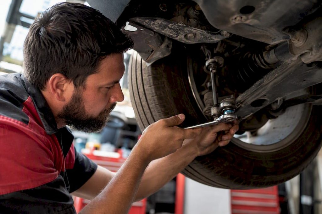 Mechanic inspecting vehicle suspension component
