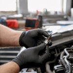 Mechanic inspecting worn spark plug in engine bay