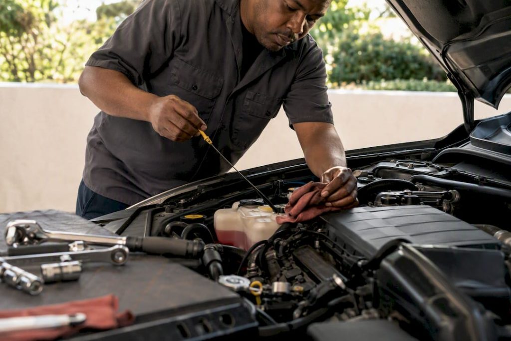 Mechanic checking vehicle fluids under hood