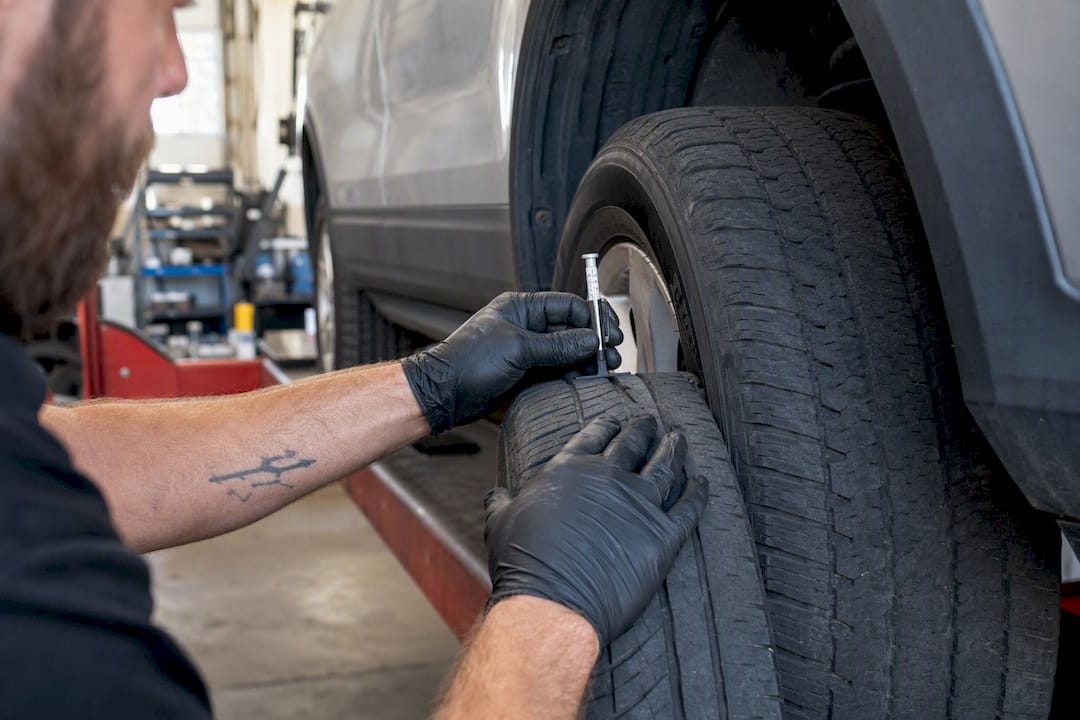 Hands measuring tire tread depth on vehicle