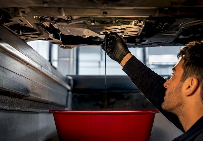 Technician draining CVT fluid beneath vehicle