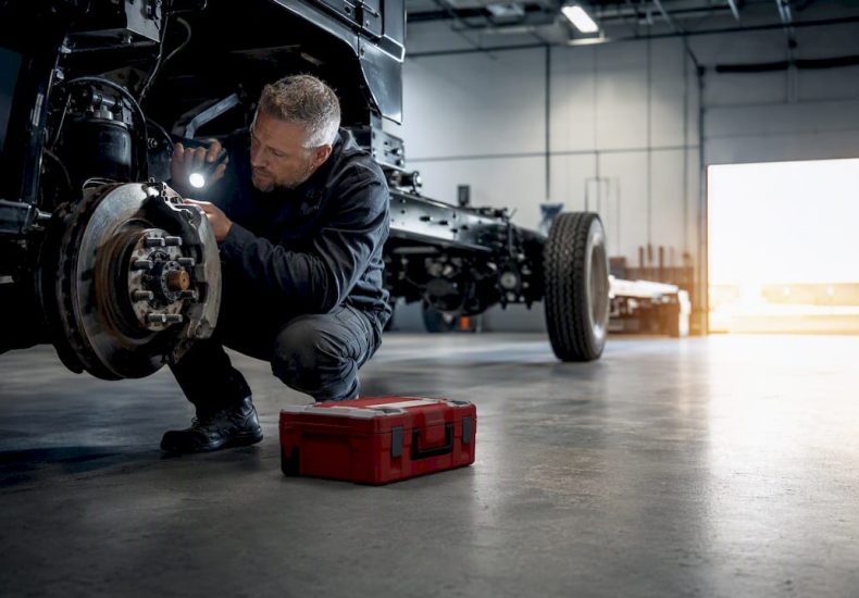 Technician inspecting fleet vehicle brake assembly