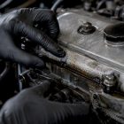 Technician inspecting an oily valve cover seam