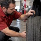 Technician measuring worn tire tread depth